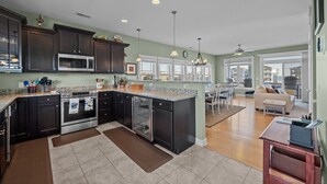 A spacious kitchen with dark cabinets, a large island, and a dining area with a view.