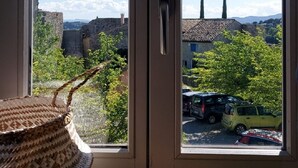 A room with a view of a historic stone wall and a tiled-roof building.
