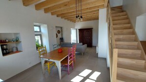 A spacious kitchen with wooden cabinets, a dining table with chairs, and a staircase leading to another level.