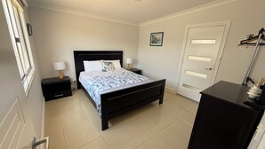 Ein Schlafzimmer mit Bett, Nachttischen, einem Kleiderschrank, einer Tür und einer Deckenleuchte.