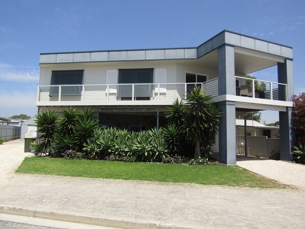 A two-story building with a flat roof and a balcony on the upper floor.