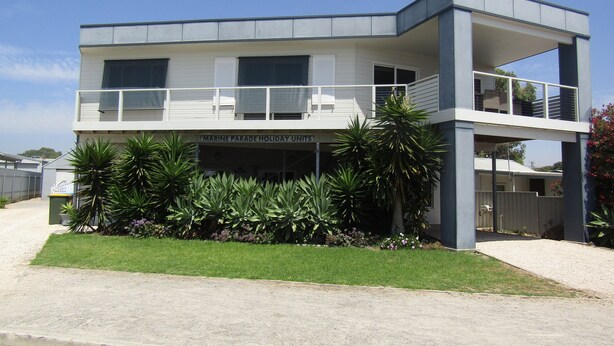 A two-story building with a flat roof and a balcony on the upper floor.