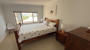 A bedroom with a bed, bedside tables, a chair, a window, and a picture on the wall.