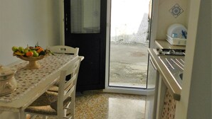 Una pequeña cocina con una mesa de comedor, sillas, un tazón de fruta y una estufa.