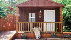 A wooden cabin with a porch, a white door, and a welcome sign.