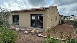 A modern house with a stone facade, large glass doors, and a garden with rocks and plants. - RECENT CORSICAN VILLA 150m2 SWIMMING POOL BEACHES LEISURE AREA (Lecci)