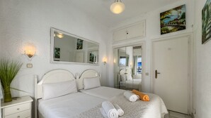 Um quarto com uma cama grande, mesa de cabeceira, espelho e porta.