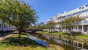 A row of white colonial-style buildings with a small bridge over a calm river. - Sunset Island - 39 Fountain Drive West 3f 3 Bedroom Condo (Ocean City)