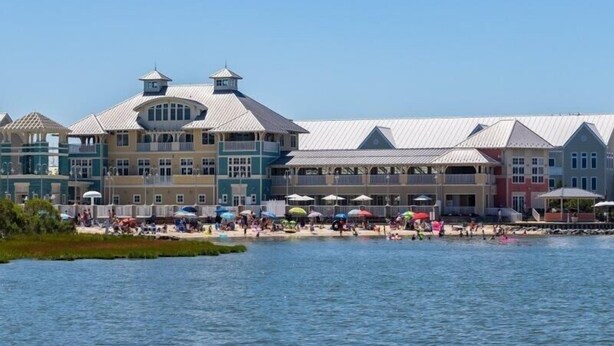A waterfront hotel with multiple balconies, a pool area, and beach umbrellas. - Sunset Island - 39 Fountain Drive West 3f 3 Bedroom Condo (Ocean City)