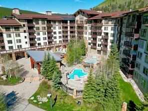 Ein mehrstöckiges Hotel mit Balkonen, einem Poolbereich und einer überdachten Terrasse.