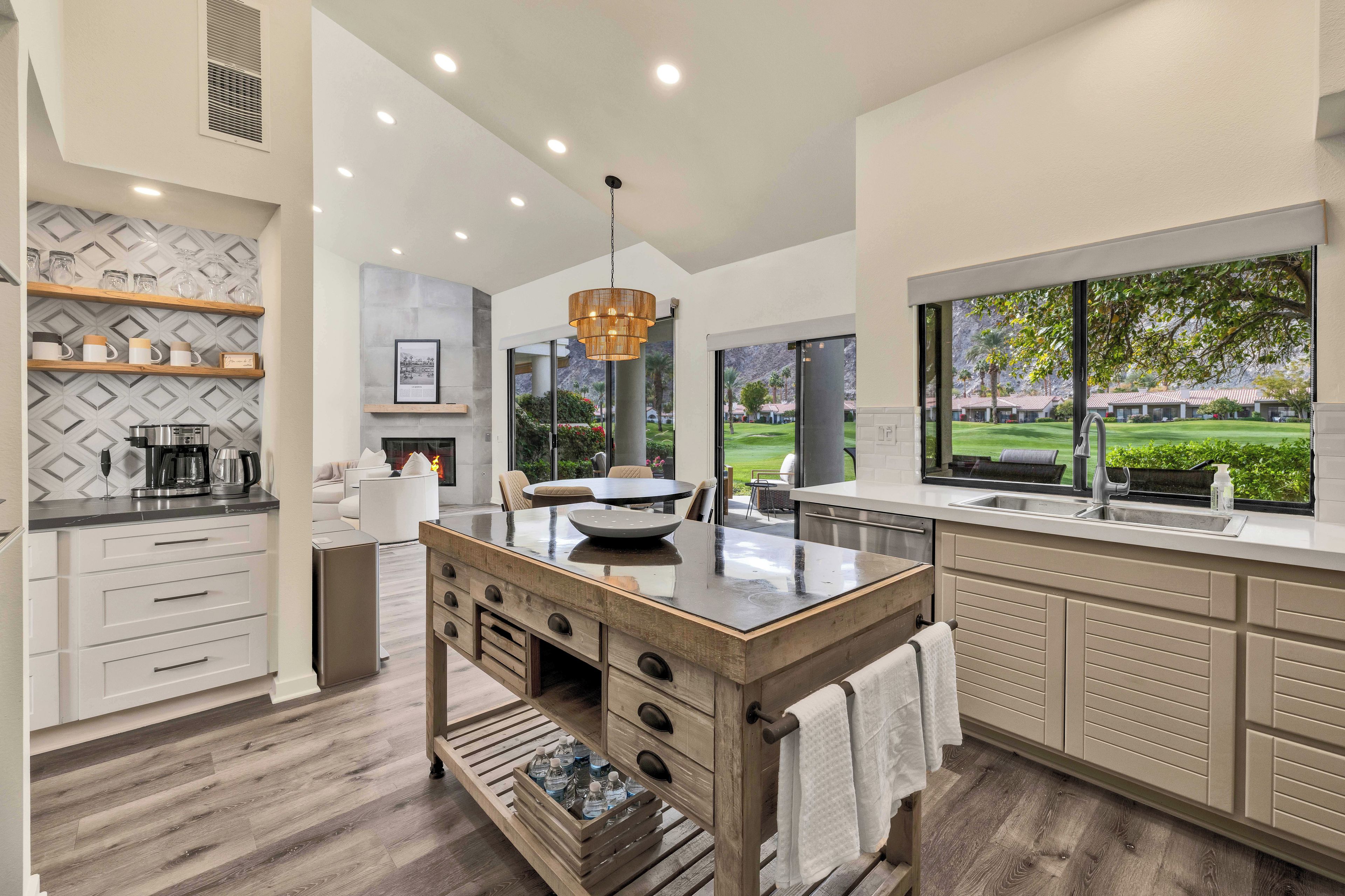 A modern kitchen with a central island, built-in appliances, and a view of a golf course.