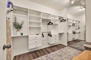 Ein begehbarer Kleiderschrank mit offenen Regalen, Kleiderstangen und Schubladen.
