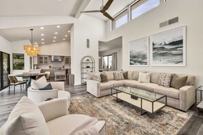 A spacious living area with a large sectional sofa, a glass coffee table, and a modern kitchen in the background.
