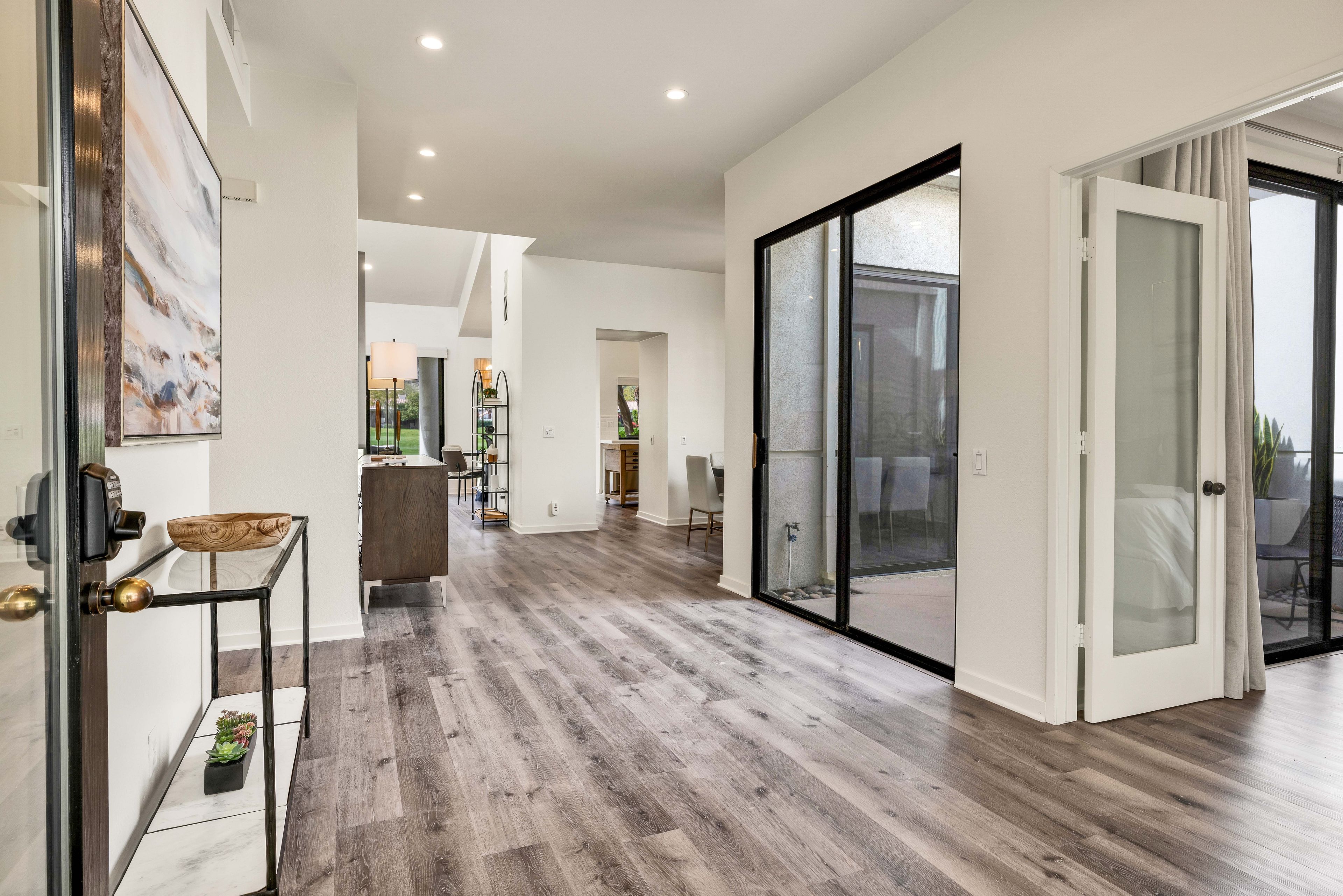 A spacious hallway with a wooden floor, a glass door leading to an outdoor area, and a modern interior design.