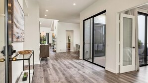 Een ruime hal met houten vloeren, een glazen deur naar een balkon, en een modern interieur.