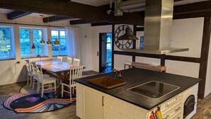 Cuina amb illa central, armaris blancs i una finestra gran amb cortines.