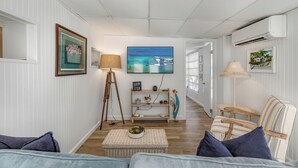 A cozy living room with a sofa, a coffee table, and a television displaying a scenic ocean view. - JUDY'S PLACE ~ 2 Bedroom, 1 Bathroom in Venture Out Community! (Cudjoe Key)