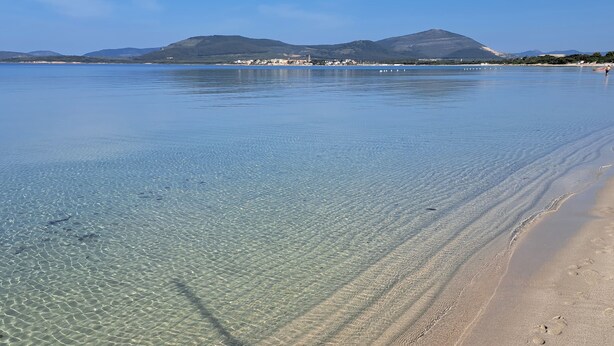 Ein sauberer Strand mit sichtbaren Fußabdrücken und ruhigem Meer.