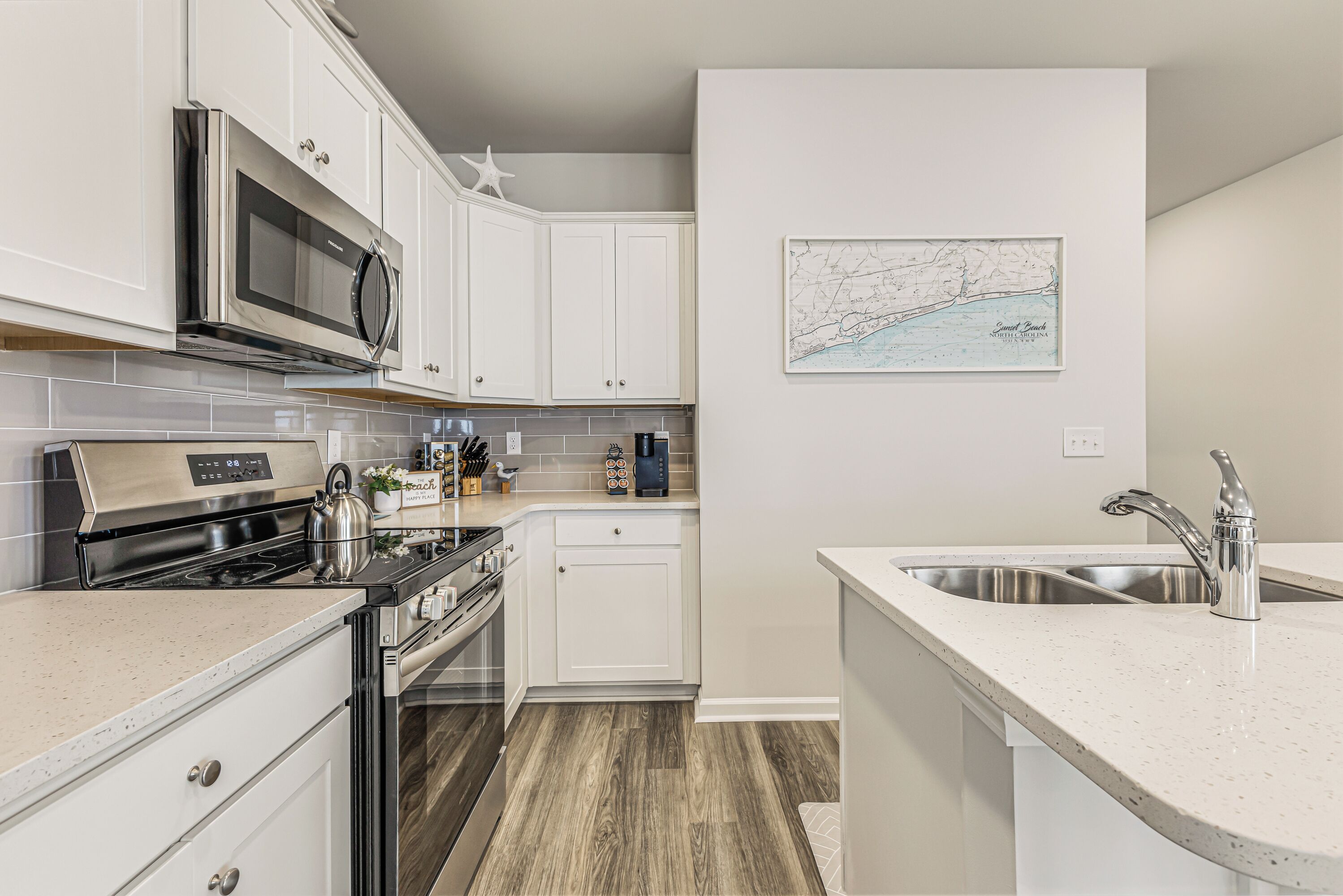 A modern kitchen with white cabinets, stainless steel appliances, and a map on the wall.