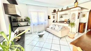 Un salon moderne comprenant un canapé, une table basse et un coin cuisine avec une cuisinière et des étagères.