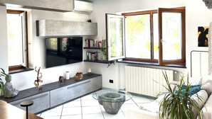 Un salon moderne doté d’un téléviseur à écran plat, d’étagères intégrées, d’une table basse en verre et d’un canapé.