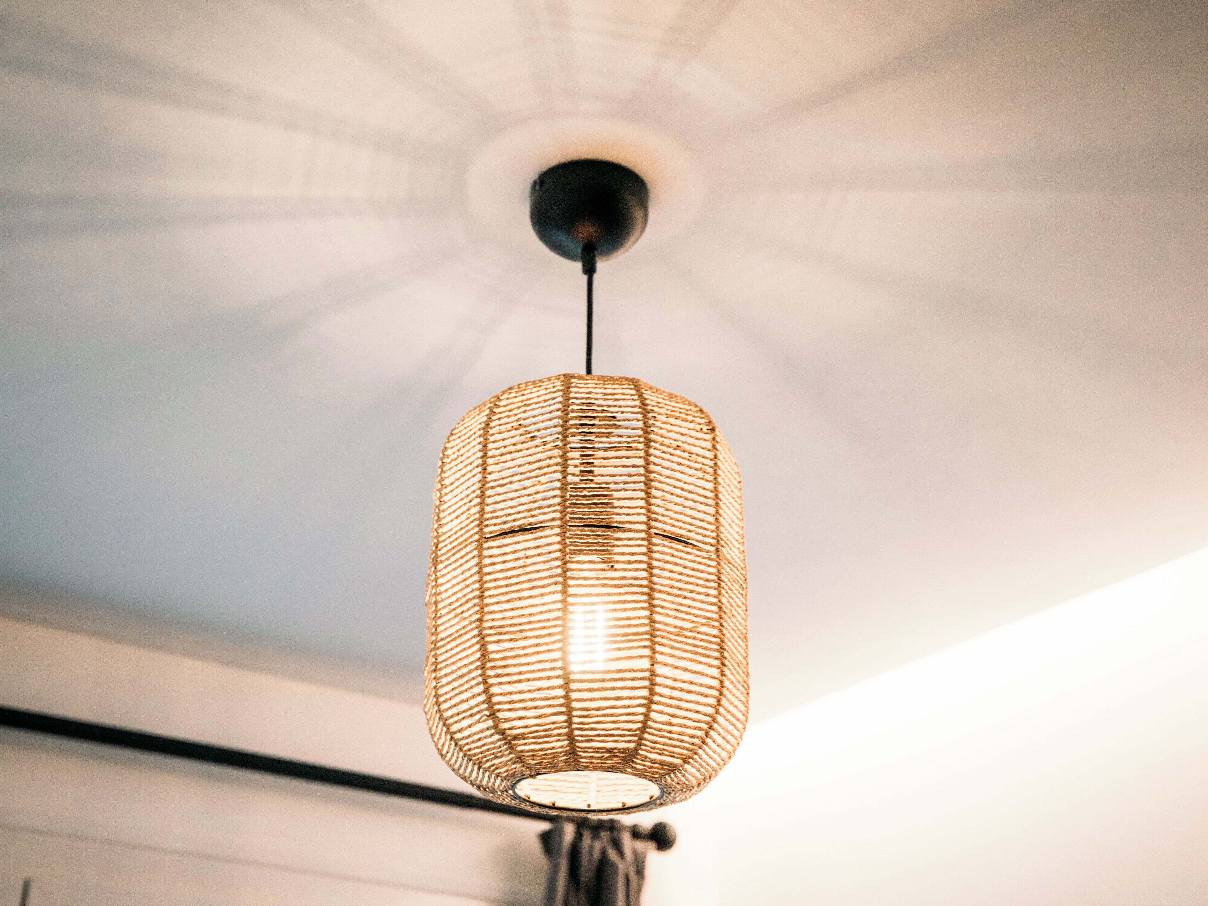 En hängande, vävd lampa med en central ljuskälla, upphängd från taket.