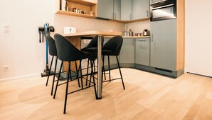 A modern kitchen with a wooden table, two black chairs, and a built-in oven. - Le Majestic - T2 en centre ville (Annecy)