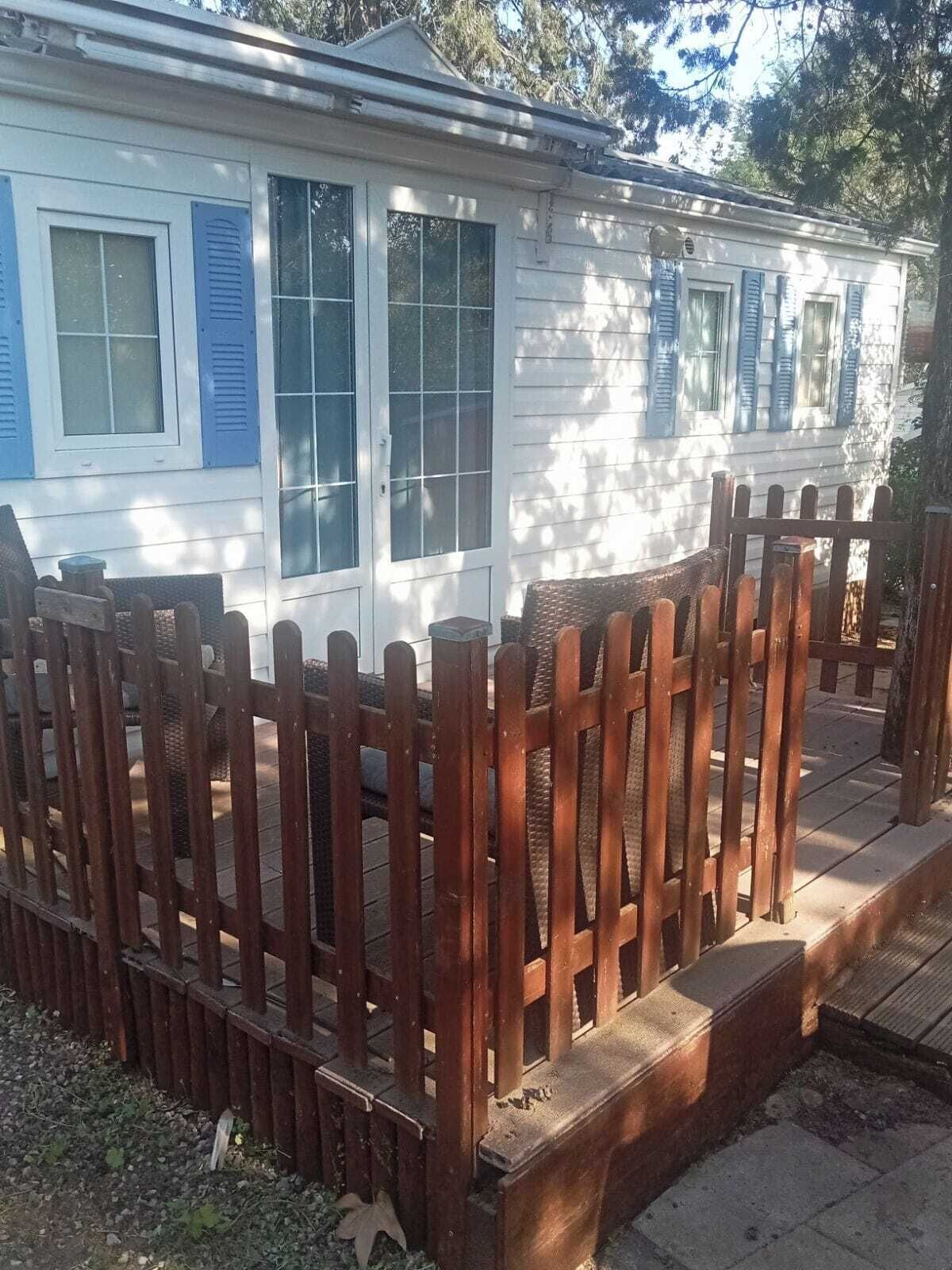 A white house with blue shutters and a wooden fence.