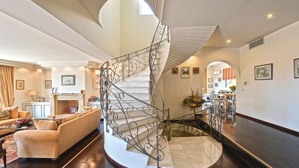 A spacious living area with a curved staircase, a fireplace, and a dining area. - VILLA DOMUS RIVIERA with exclusive pool and breathtaking panoramic views (Voula)