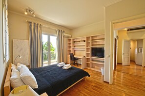 Ein geräumiges Schlafzimmer mit einem großen Bett, einem Schreibtisch und einem Fernseher.