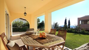 An outdoor patio with a wooden table, chairs, and a fruit bowl. - VILLA DOMUS RIVIERA with exclusive pool and breathtaking panoramic views (Voula)