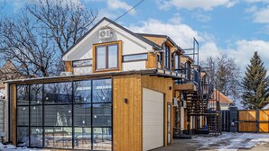 Una casa moderna con un ampio garage, rivestimento in legno e un piccolo balcone.