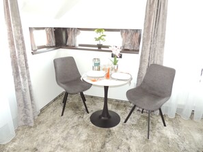 A corner room with two grey chairs, a small round table, and a window with curtains. - Premont Luxury Ghimbav (Ghimbav)
