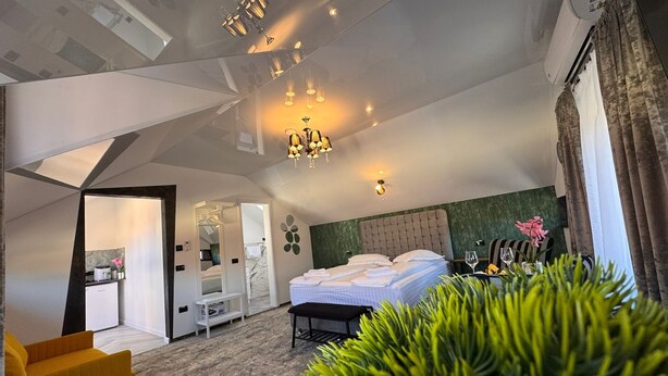 Una camera d'albergo moderna con un letto grande, un'area salotto e vista sulla città.