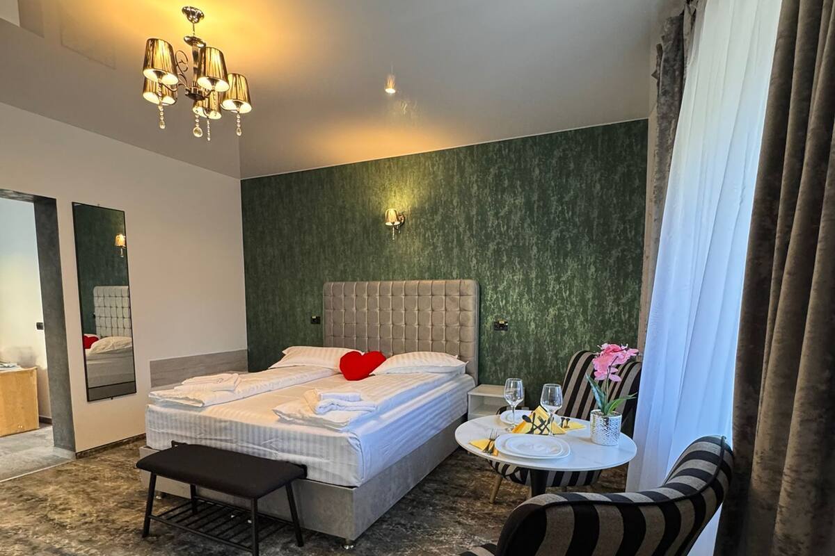Una habitación de hotel moderna con una cama grande, una mesa de comedor, una silla y una planta pequeña.