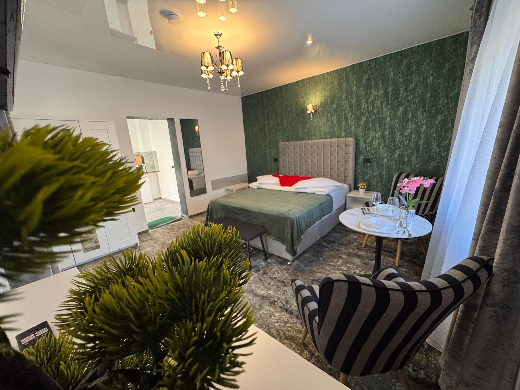 Ein modernes Hotelzimmer mit Bett, Nachttisch und einem kleinen runden Tisch mit Blumen in einer Vase.