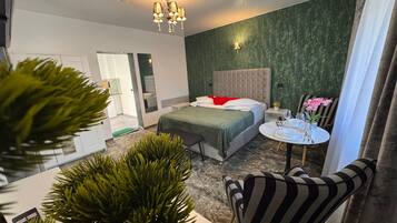 Ein modernes Hotelzimmer mit Bett, Nachttisch und einem kleinen runden Tisch mit Blumen in einer Vase.