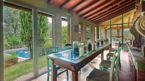 A covered patio with a glass table and chairs, a pool, and a view of the surrounding greenery. - Giunchette Meri, Cavriglia, Arezzo and Cortona (Cavriglia)