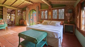 A cozy room with a large bed, a wicker chair, and a view of the outdoors through a window. - Giunchette Meri, Cavriglia, Arezzo and Cortona (Cavriglia)