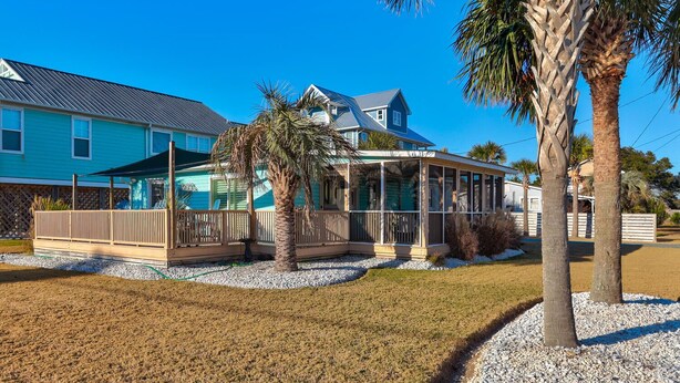 Une propriété située en bord de mer, dotée d’un patio couvert, d’une piscine et d’une grande maison avec un toit bleu.