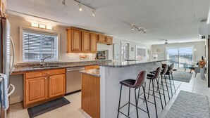 Une cuisine moderne avec des meubles en bois, un plan de travail en granit et un coin bar avec des tabourets.