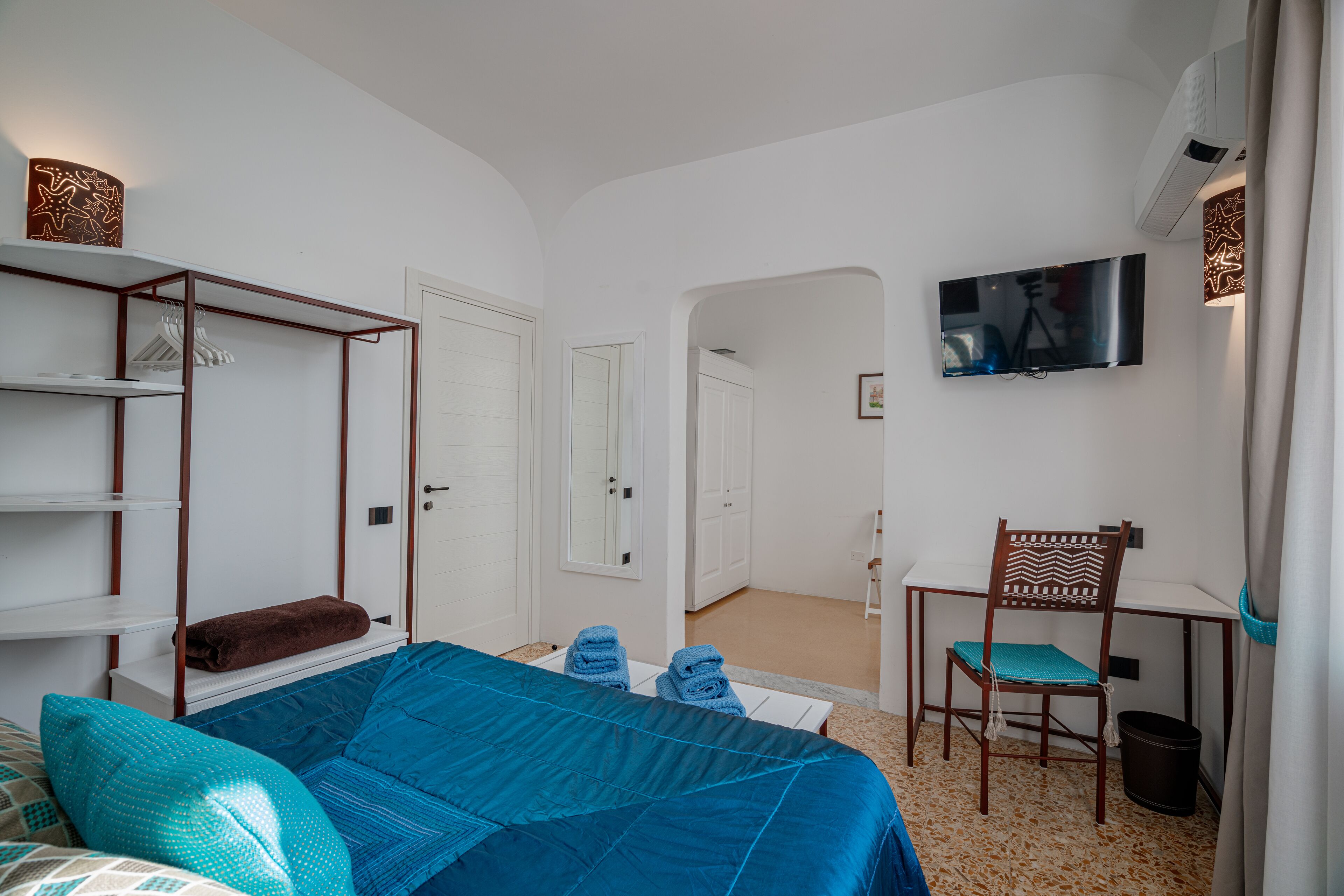 A bedroom with a bed, a desk, a chair, a TV, and a wardrobe.