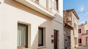 Une ruelle étroite pavée, bordée d’immeubles dotés de balcons et de fenêtres.