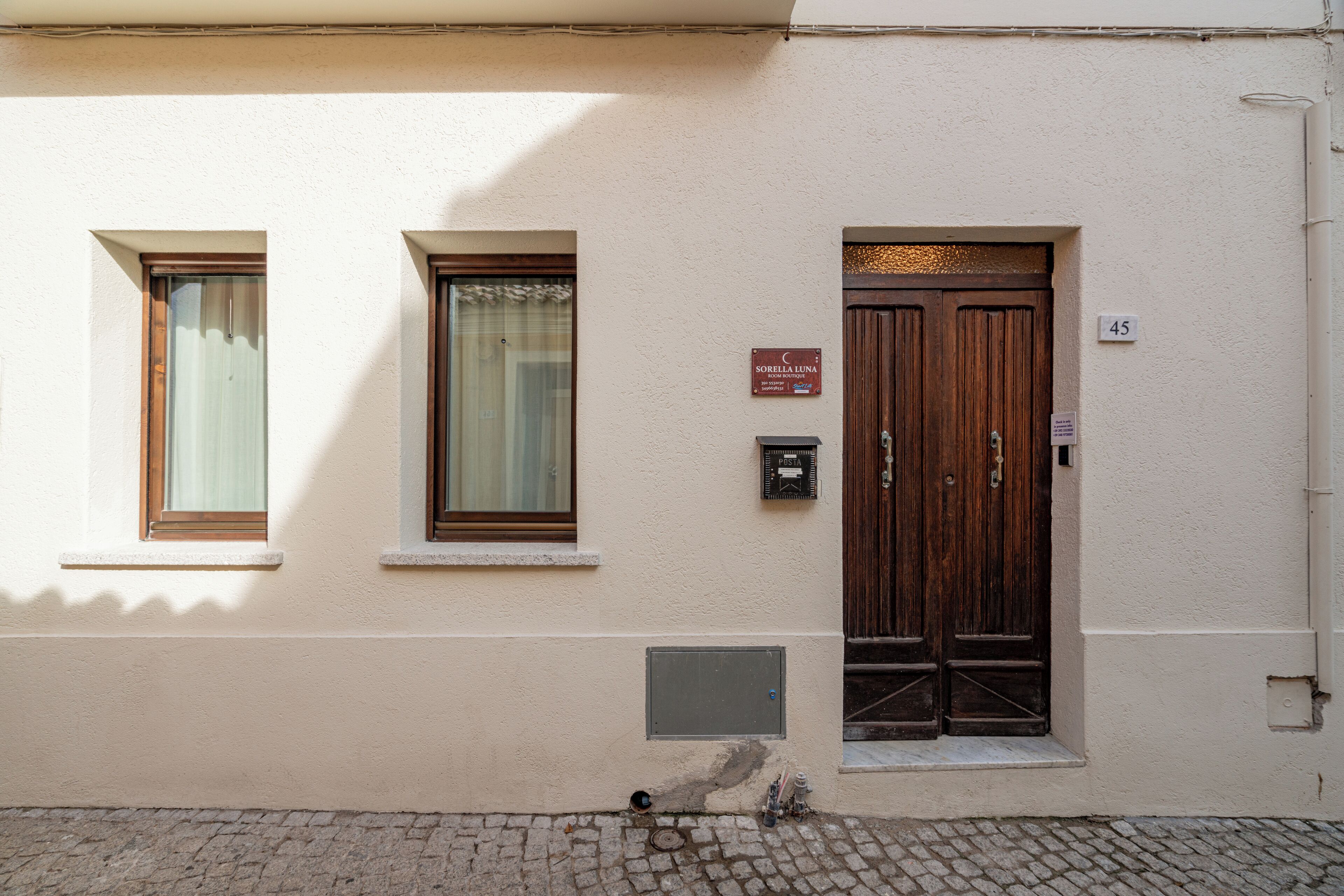 Une façade d’immeuble avec deux fenêtres, une porte en bois et une enseigne indiquant le nom « Sorella Luna ».