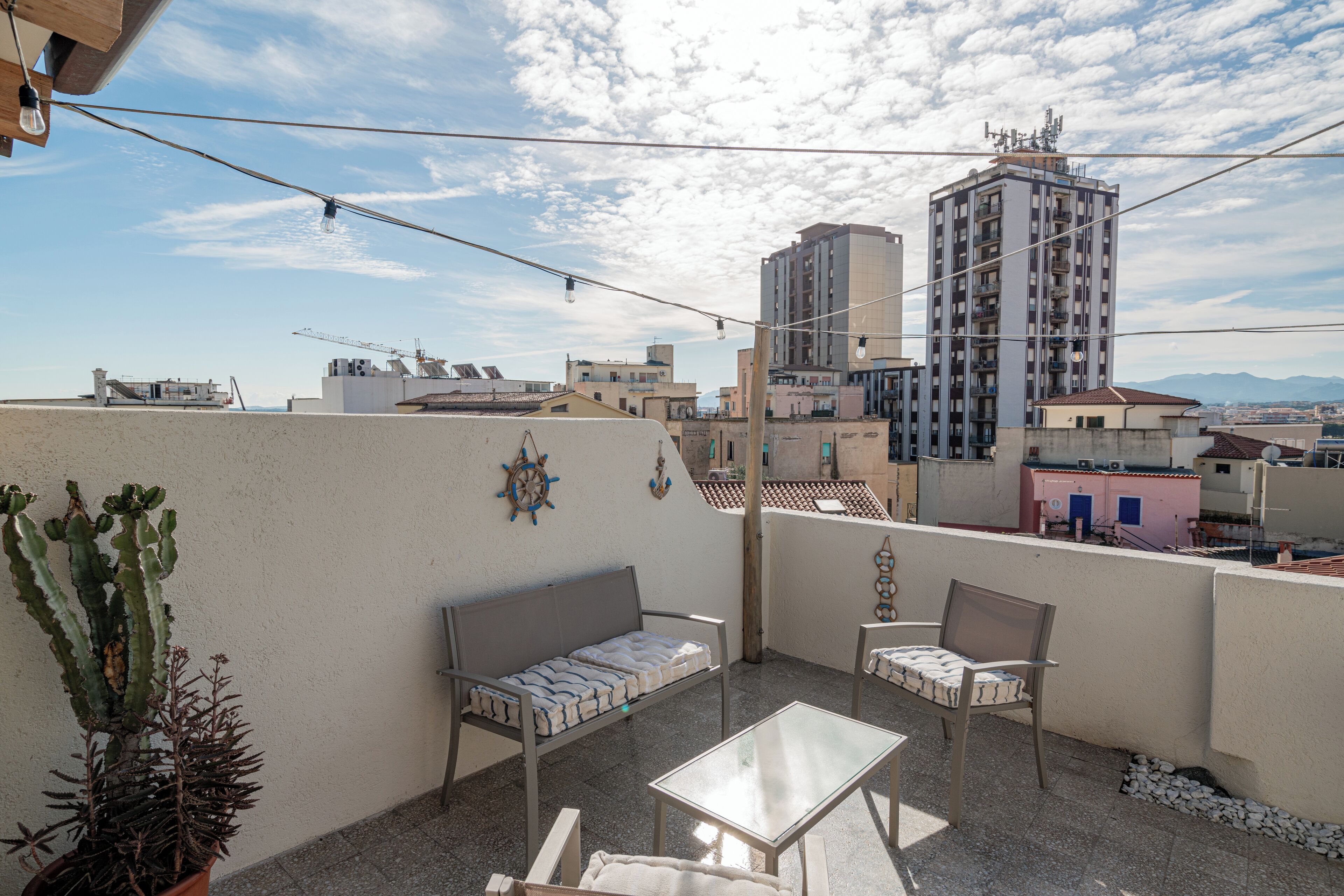A rooftop terrace with a sofa, chairs, and a table.