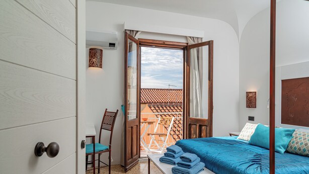 Une chambre avec un lit, une table avec des serviettes, une chaise et une vue sur l’extérieur.