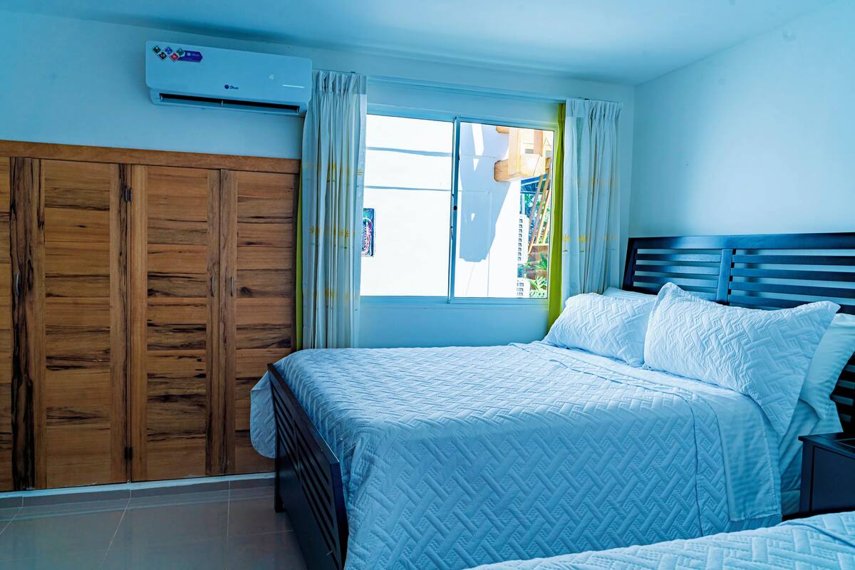 Un dormitorio con cama, armario de madera y aire acondicionado.