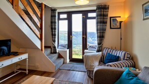 En hyggelig stue med en sofa, et træskrivebord og en trappe op til en balkon.