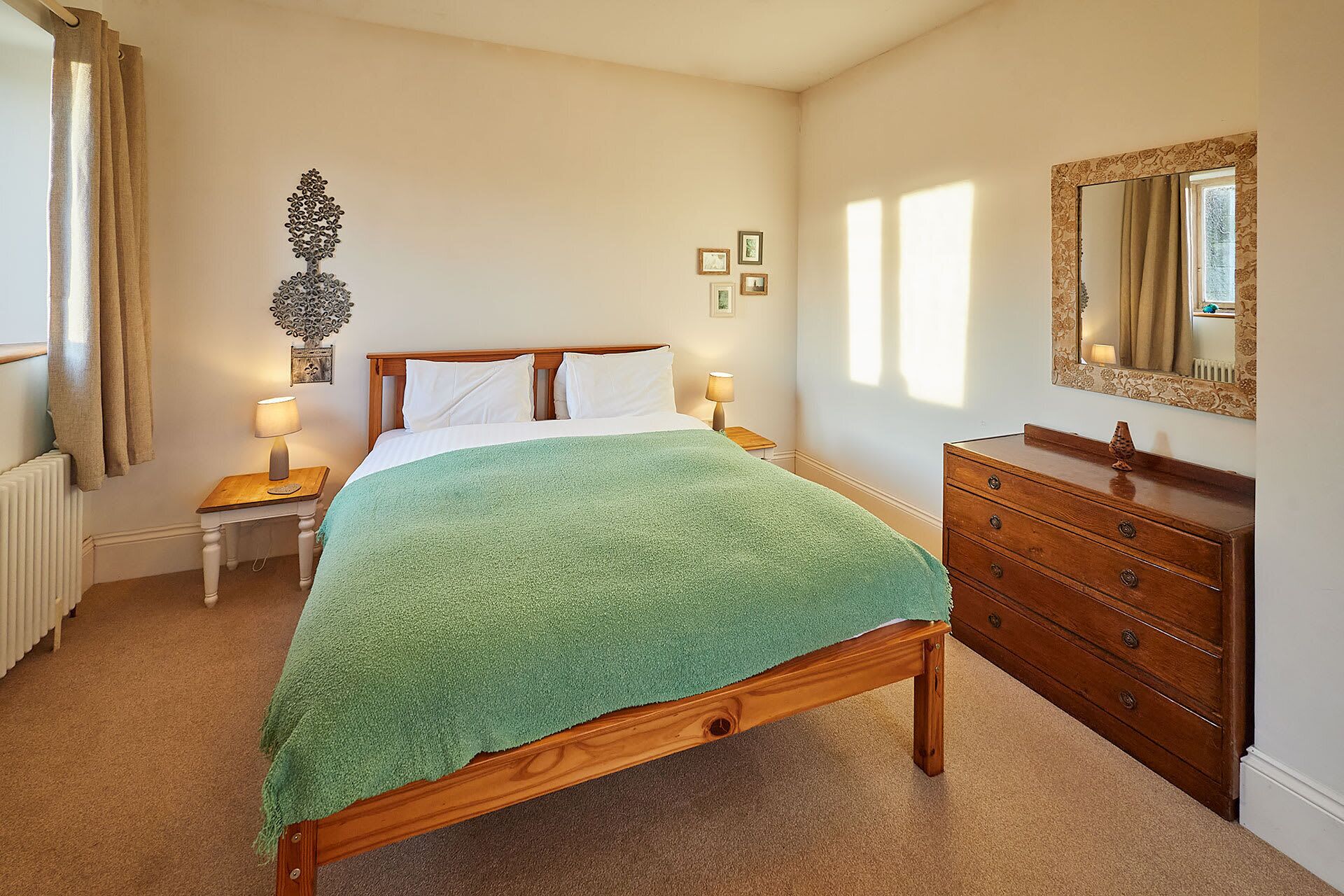 Une chambre à coucher avec un lit en bois, une commode, un miroir et un radiateur.
