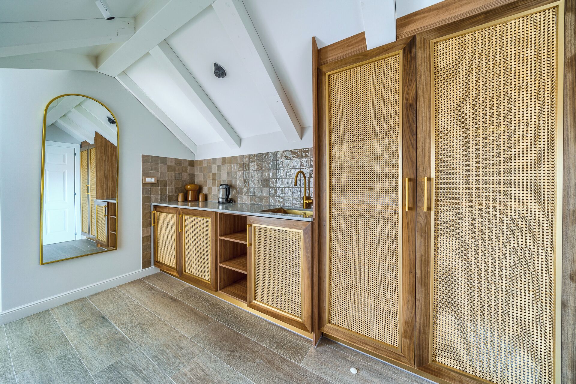 A modern kitchen with a large island, wooden cabinets, and a large mirror.